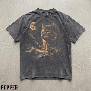 May include: A charcoal grey short-sleeve t-shirt featuring a graphic print of a large cat face and a smaller cat standing on a mountain ridge under a full moon. The shirt has a washed-out, vintage-style texture and the word PEPPER printed below.