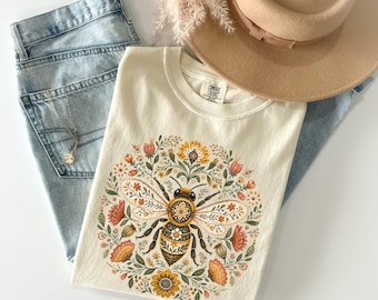 Maglietta con ape in stile folk art, maglietta con ape e fiori, maglietta botanica con impollinatore, maglietta cottagecore a tema natura, regalo per amanti delle api e giardinieri, colori comodi