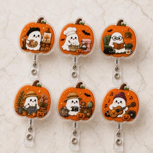 May include: Six orange pumpkin-shaped badge reels featuring white ghosts engaged in various activities: painting, baking, reading, gardening, traveling, and playing guitar. Each ghost is depicted with distinct accessories like hats, books, or instruments, set against a bright orange pumpkin background with small decorative elements like bats and stars.