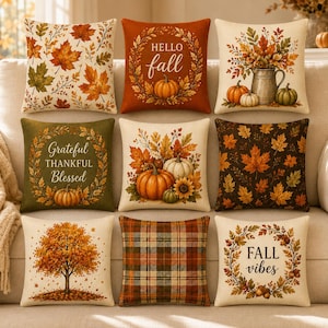 May include: A set of nine square throw pillows featuring autumn-themed designs. Patterns include maple leaves, pumpkins, plaid, and trees. Text on pillows reads HELLO fall, Grateful THANKFUL Blessed, and FALL vibes in various colors and fonts.