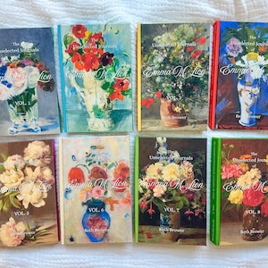 May include: A collection of eight hardcover books titled The Unselected Journals of Emma M. Lion by Beth Brower, volumes 1 through 8. Each book cover features a unique, colorful floral still life painting in a vase, with distinct spine colors.