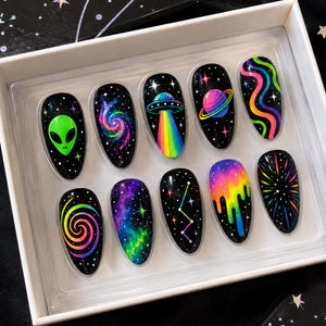以下が含まれることがあります： 黒い背景に宇宙をテーマにしたデザインが施された、アーモンド型のプレスオンネイル10本セット。緑色のエイリアンの頭、カラフルな銀河、虹色の光線を放つUFO、輪のある惑星、ネオンの波、渦巻き、星などが描かれています。