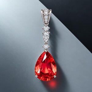 May include: A silver-toned pendant featuring a large, pear-shaped, vibrant red gemstone at the base. The pendant is suspended from a vertical arrangement of smaller, round, and pear-shaped clear stones set in a metallic frame with a decorative bail.