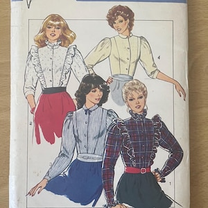 May include: Vintage sewing pattern titled "Style" with illustrations of blouses. The pattern includes sizes 10, 12, and 14. The cover features a blue and white design with the number 3799.