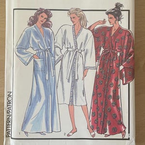 Peut inclure: Un paquet de patrons de couture vintage avec des illustrations de trois robes différentes. Le paquet est étiqueté "Style" avec le numéro 1427 et la taille MD. Les robes sont de couleur bleue, blanche et à motifs floraux rouges.