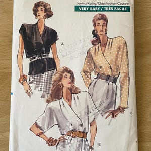 May include: A vintage Very Easy Very Vogue sewing pattern. The cover shows illustrations of women's fashion designs, including a black top, a beige polka-dot top, and a white top. The pattern number is 7537, and the size is (12-14-16).