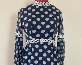 May include: A navy blue dress with white polka dots and white crocheted trim around the neckline and sleeves.