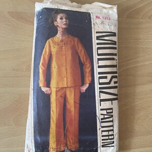 May include: Vintage sewing pattern envelope showing a woman wearing a yellow trouser suit with decorative trim. The pattern is labelled "Multi-Size Pattern" and "No. 1578".