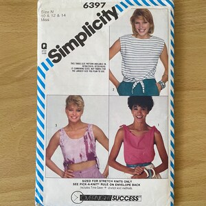 May include: A vintage Simplicity sewing pattern envelope featuring four top designs. The envelope is white with blue diagonal stripes and the number 6397. The top designs include a striped top, a tie-dye top, and a pink top. The text "OVERNIGHT SUCCESS" is visible.