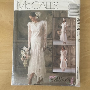 May include: A McCall's sewing pattern for bridal gowns. The pattern includes three dress designs, such as a long-sleeved lace dress and a shorter, cap-sleeved style. The pattern size is 12.