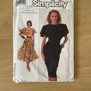 Può includere: Modello Simplicity 1225 di Cathy Hardwick. Il modello include le istruzioni per due abiti. Un abito è un abito midi nero con maniche corte e scollo rotondo. L'altro abito è un abito midi con stampa floreale colorata con maniche corte e scollo rotondo.