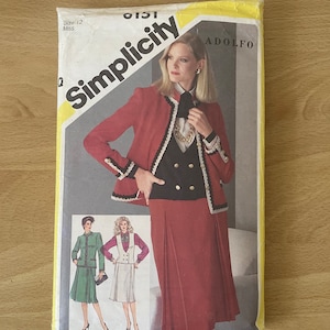 May include: Simplicity sewing pattern number 0151 by Adolfo. The pattern is for a women's jacket and skirt set. The model is wearing a red jacket with black trim, a black vest, and a red skirt. The pattern includes instructions for making a green jacket and skirt set and a white jacket and skirt set.