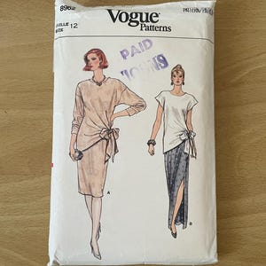 Op de afbeelding: Vogue Patterns naaipatroon envelop voor een jurk met twee verschillende stijlen. Het patroon is voor maat 12 en heet "Paid  " met een paarse stempel over het woord "toons".