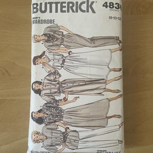 Pode incluir: Um pacote de padrões de costura Butterick vintage com ilustrações de designs de roupas femininas. O pacote é branco com o nome da marca e o número do padrão impressos em preto. Os designs incluem vestidos e conjuntos. O tamanho é 8-10-12.