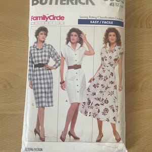 May include: A vintage Butterick sewing pattern envelope featuring three dress designs. The envelope includes the text "BUTTERICK", "Family Circle Collection", and "EASY/FACILE". The dresses are shown in different styles, including a button-down dress and a floral print dress.