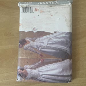 Könnte beinhalten: Ein Butterick-Schnittmuster für ein Brautkleid. Das Schnittmusterpaket zeigt Illustrationen der Kleiderdesigns in Weiß- und Cremetönen. Die Verpackung ist leicht abgenutzt.