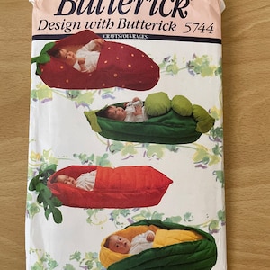 May include: A vintage sewing pattern from Butterick, design number 5744, for making baby sleeping bags shaped like a strawberry, pea pod, carrot, and corn. The pattern includes instructions for crafts and ouvrages.