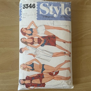 May include: A retro sewing pattern packet with the word "Style" in blue. The packet shows illustrations of women in swimwear and summer outfits. The pattern is for sizes 10, 12, 14, and 16.