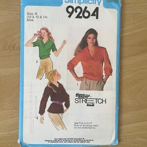 May include: Simplicity sewing pattern number 9264 for a knit top. The pattern is for sizes 10, 12, and 14. The pattern shows three different styles of tops, one with a collar, one with a V-neck, and one with a mock neck.
