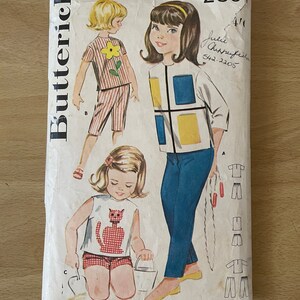 Peut inclure: Patron de couture vintage pour une tenue de fille. Le patron est pour une robe avec un motif géométrique, une chemise avec un motif de chat et un short avec un motif de fleur. Le patron est de Butterick et est de taille 4, pour un tour de poitrine de 23 pouces.