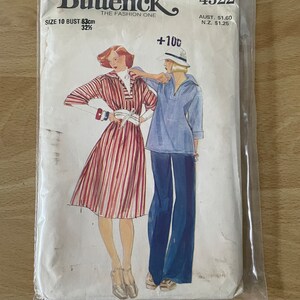 Pode incluir: Envelope de padrão de costura vintage para um vestido e uma blusa para mulher. O padrão é Butterick 4322, tamanho 10, busto 83 cm. O vestido é de riscas vermelhas e brancas com colarinho de marinheiro e a blusa é azul com colarinho de marinheiro. O padrão é para um busto de 83 cm, tamanho 10.