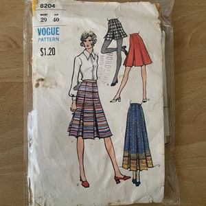 Puede incluir: Patrón de costura vintage Vogue número 8204 para una falda. El patrón incluye instrucciones para tres estilos de faldas diferentes: una falda corta plisada con rayas, una falda larga de línea A con estampado floral y una falda corta de línea A con estampado a cuadros. El patrón tiene un precio de $ 1,20.