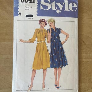 Peut inclure: Patron de couture vintage pour une robe, taille 14, avec deux mannequins portant la robe en jaune et bleu. Le numéro du patron est 3341 et la marque est Style.
