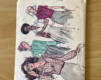 May include: A vintage sewing pattern envelope for a blouse with a bow. The pattern is from Very Easy Vogue Patterns and is size 12. The envelope features four illustrations of women wearing different versions of the blouse.