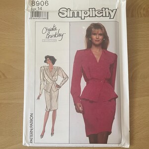 Könnte beinhalten: Simplicity Schnittmuster 8906, Christie Brinkley Collection, Größe 14. Das Schnittmuster zeigt eine Frau in einem roten Anzug mit Schößchenjacke und Bleistiftrock. Eine weitere Abbildung zeigt einen cremefarbenen Anzug.