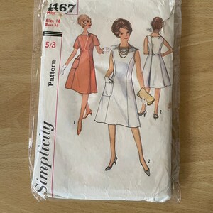 May include: Vintage Simplicity sewing pattern #1467 for a dress. The pattern is for size 16, bust 36. The pattern shows three different views of the dress, one in a peach colour, one in white, and one in white with a button detail on the back.