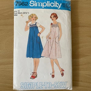 Może przedstawiać: Wzór szycia Simplicity numer 7962 na sukienkę. Wzór jest dla rozmiaru 10, obwód biustu 83 cm. Wzór przedstawia dwie modelki w sukienkach, jedna w niebieskim wzorze w kratę, a druga w czerwono-białym wzorze w kratę. Wzór jest oznaczony jako "Simple-to-Sew".