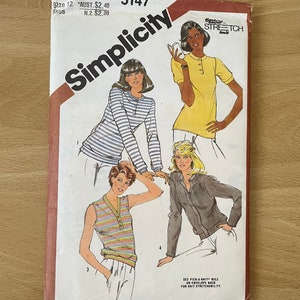 Pode incluir: Padrão de costura Simplicity vintage com ilustrações de quatro tops diferentes. O envelope é principalmente branco com uma borda vermelha e o logotipo Simplicity. As ilustrações incluem uma camisa de manga comprida listrada, uma camiseta amarela de manga curta, um top sem mangas listrado e um casaco abotoado.