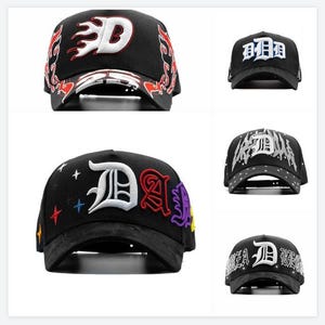 May include: Black baseball caps with embroidered designs. One cap features a white "D" with flames, while others display "D" and other letters in various colours. Some caps have star accents.