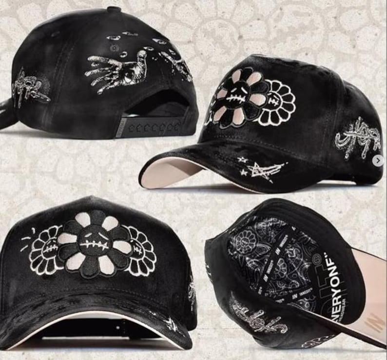 May include: A black baseball cap featuring white embroidered graphics of a sad flower with stitched mouth, stars, and hand motifs. The cap has a structured crown, a curved brim with a light-colored underside, and an interior lining with text.