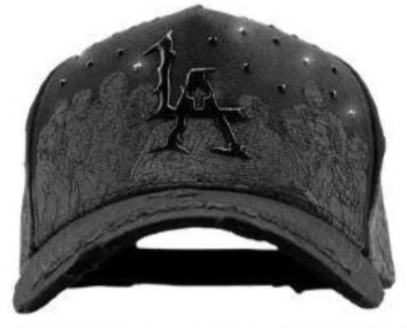 May include: Black baseball cap with a curved brim. The cap features the letters "LA" in a stylized design on the front. The cap has a textured pattern and small studs on the crown.