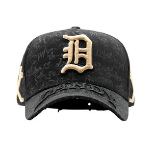 May include: Black baseball cap with a gold embroidered letter "D" on the front. The cap has a textured pattern and gold accents on the sides. The brim features embossed text.