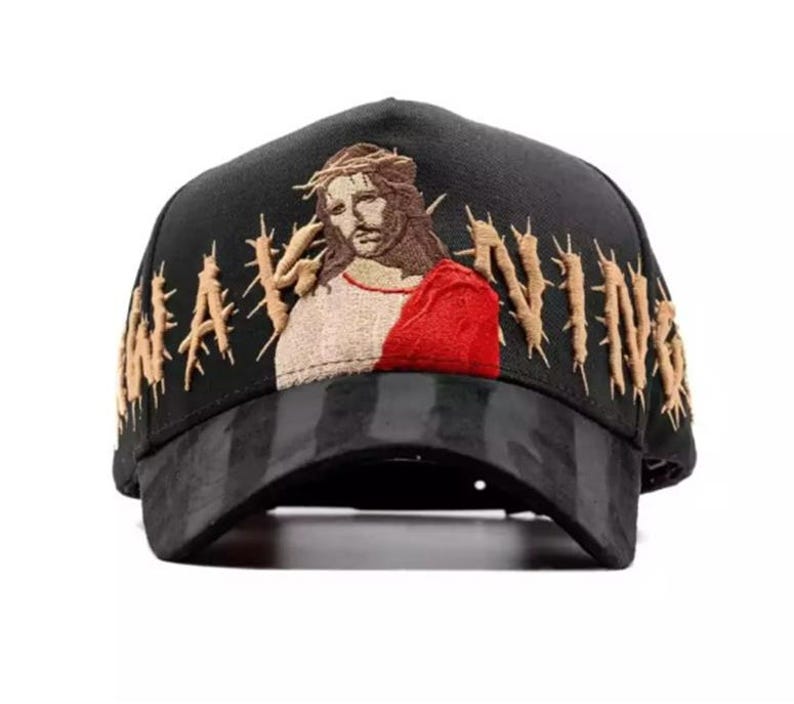 May include: Black baseball cap with an embroidered image of Jesus wearing a crown of thorns and a red robe. The word "NAVIN" is embroidered in gold thread on the side of the cap.