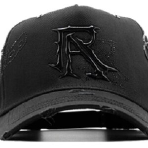 May include: Black baseball cap with a distressed brim. The cap features a large, stylized "R" on the front and decorative stitching on the sides. The overall design is dark and edgy.