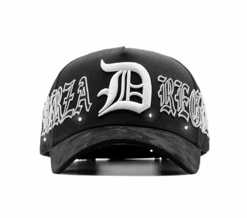 May include: Black baseball cap featuring white embroidered text and a large white letter "D". The text "FORZA DREGS" is embroidered on the cap. The cap has a curved peak and a structured crown.