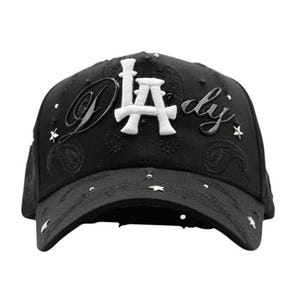 May include: Black baseball cap with white "LA" lettering and "dy" script. The cap features star-shaped embellishments and paisley patterns. A stylish accessory for casual wear.