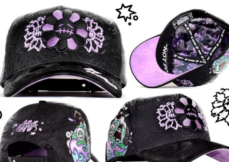 May include: A black baseball cap featuring an embroidered purple and black flower with a stitched face on the front. The cap has a textured black surface, a glossy brim, and a purple underside. The interior lining displays purple and black graphics.