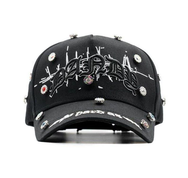 May include: Black baseball cap featuring the word "DARK" embroidered in a gothic style. The cap is adorned with decorative jewels and the text "dark as" on the brim.