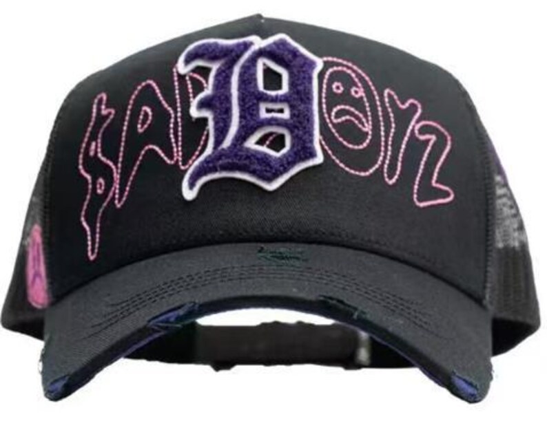 May include: Black trucker cap featuring the word "SABOIZ" embroidered in pink and purple. The letter "B" is in a purple patch with a white outline. The cap has a distressed brim and mesh back.