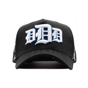 May include: Black baseball cap featuring the letter "D" in white and blue embroidery. The cap has a curved peak and a structured crown. The design is a bold, eye-catching statement piece.
