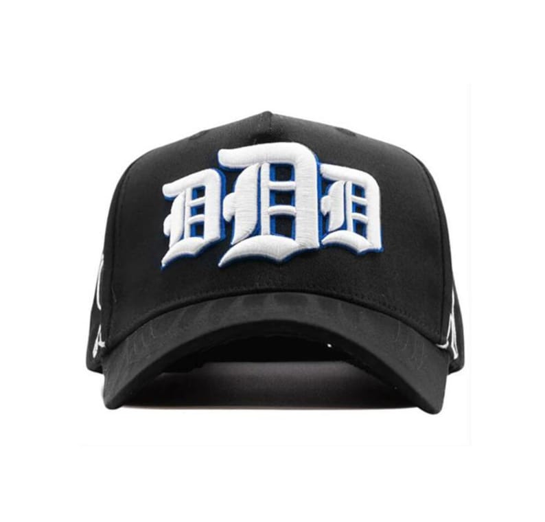 May include: Black baseball cap featuring the letter "D" in white and blue embroidery. The cap has a curved peak and a structured crown. The design is a bold, eye-catching statement piece.