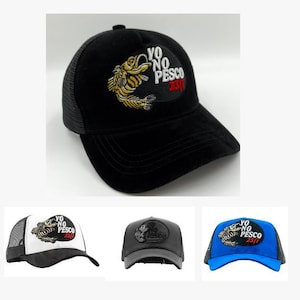May include: Black baseball cap with a mesh back and a curved peak. The cap has an embroidered patch with a fish design and the text "YO NO PESCO 23/7". Other caps in white, grey, and blue are also shown.