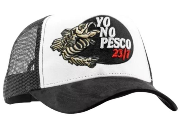 May include: A black and white trucker cap with a mesh back. The front panel displays a fish skeleton graphic and the text "YO NO PESCO 23/7" in white and red.