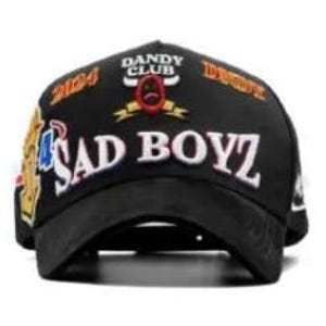 Może przedstawiać: Czarna czapka z daszkiem z białym napisem "SAD BOYZ" i "DANDY CLUB" nad małym emblematem. Czapka posiada r&oacute;wnież liczby "2024" oraz inne grafiki w kolorze złotym, czerwonym i niebieskim.