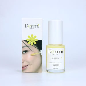 May include: A white rectangular box and a clear glass bottle of Dermi Paris Vita Glow brightening serum. The box features the brand name, a yellow flower icon, and a photo of a face with a dropper. The bottle has a white cap and yellow liquid.