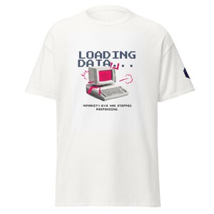 Può includere: T-shirt bianca con grafica pixelata di un vecchio computer con schermo rotto e la scritta "LOADING DATA..." sopra. Sotto, il testo recita "HUMANITY.EXE HAS STOPPED RESPONDING."